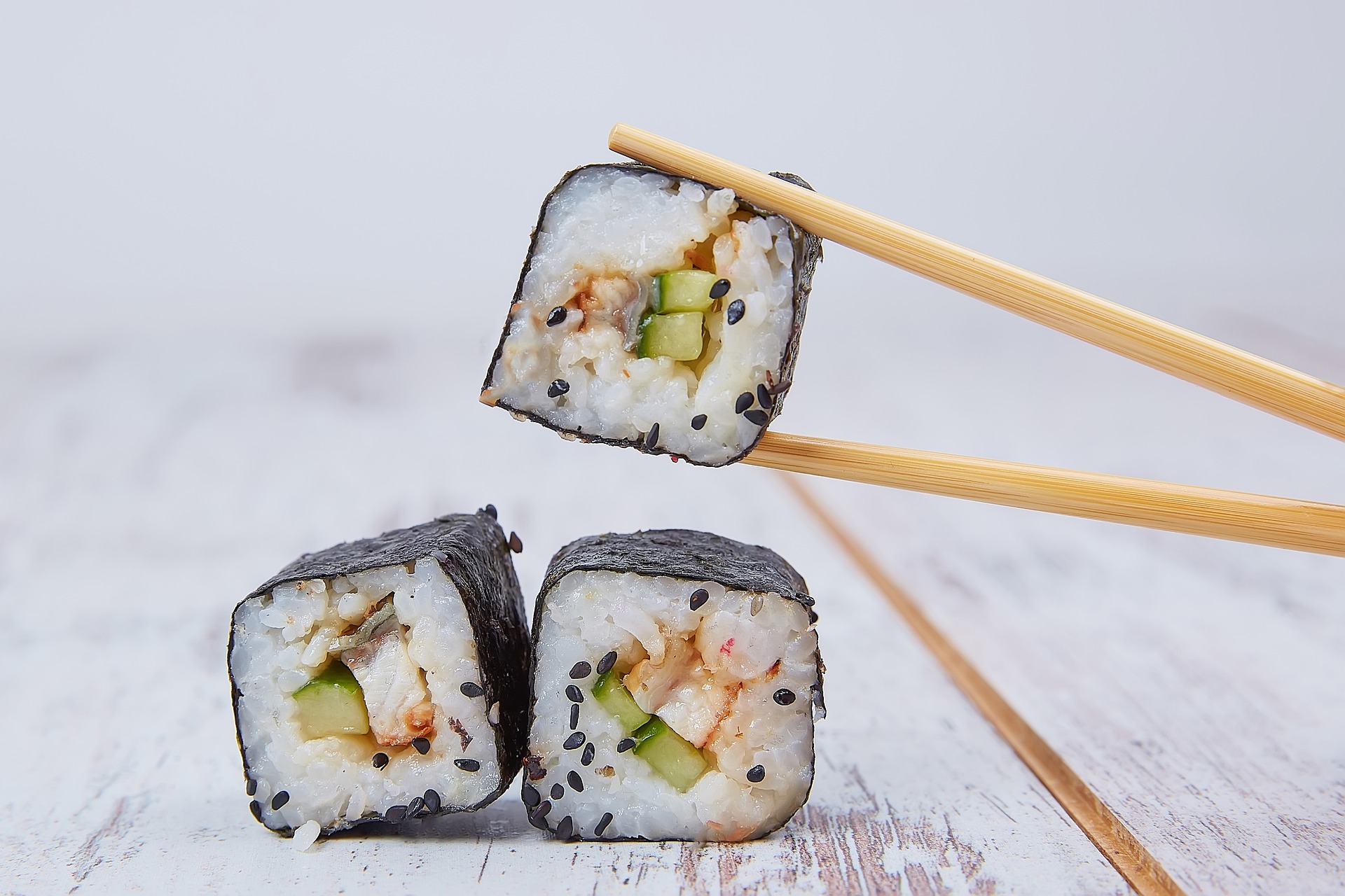 A Sushi roll being held in chopsticks